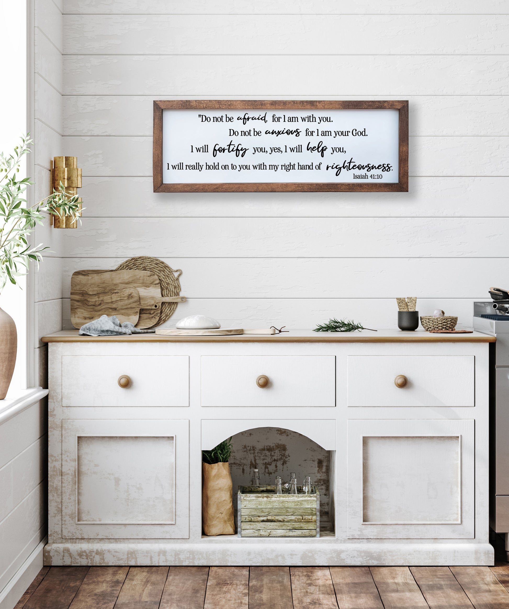 White wooden cabinet with a framed quote above it in a kitchen setting.