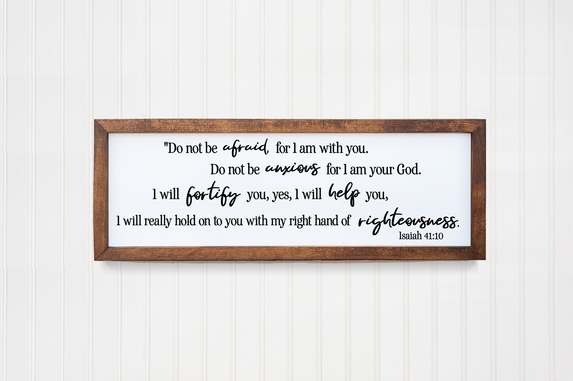 Wooden framed sign with biblical text on a white wall