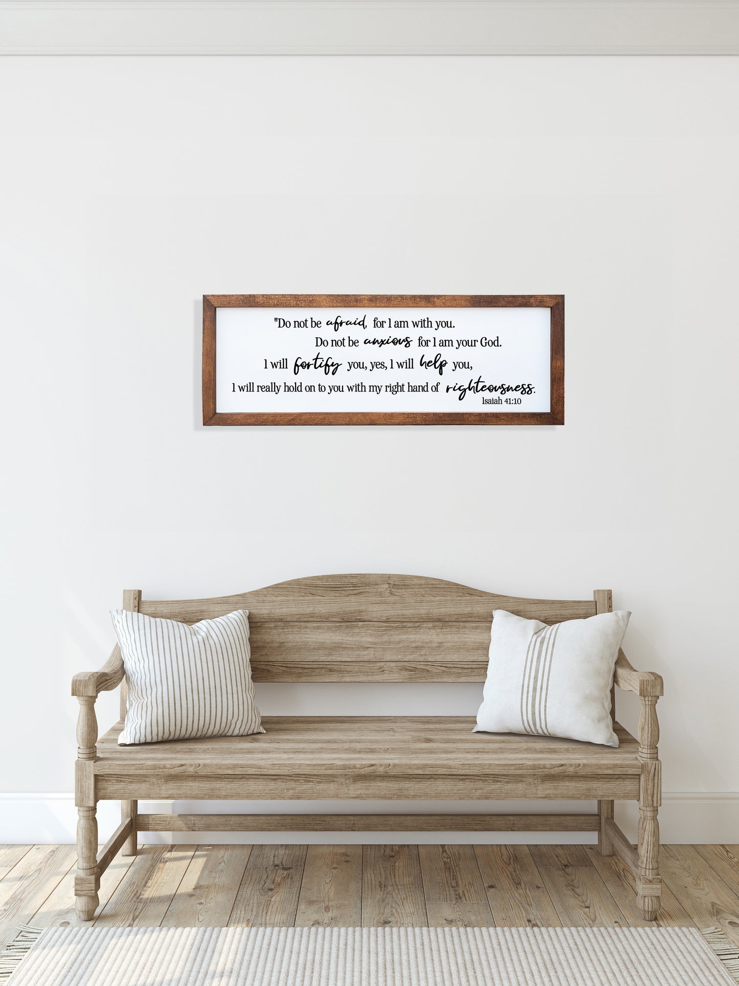 Wooden bench with white pillows in a room with a framed quote on the wall.