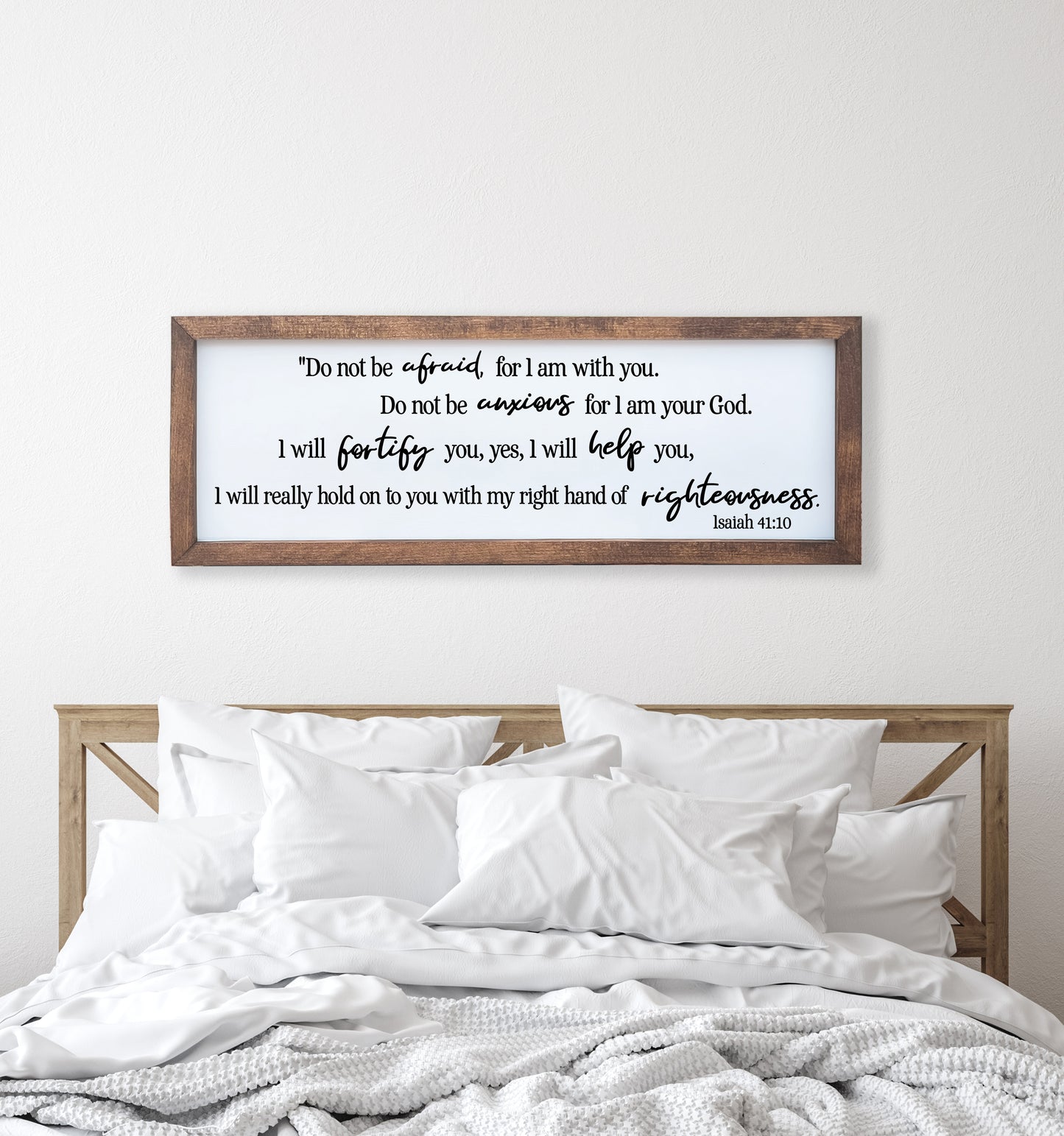 Framed biblical verse above a bed with white bedding