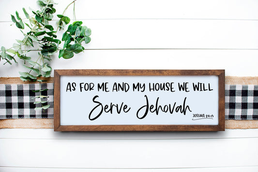 A wooden sign with a Bible verse 'As for me and my house, we will serve Jehovah' written on it, placed on a white wooden surface with a green plant and a checkered pattern in the background.